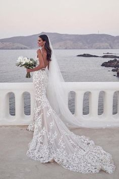 a woman in a wedding dress standing by the water