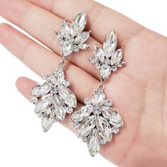 a pair of earrings is being held in someone's hand