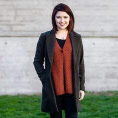 a woman standing in the grass with her hands in her pockets