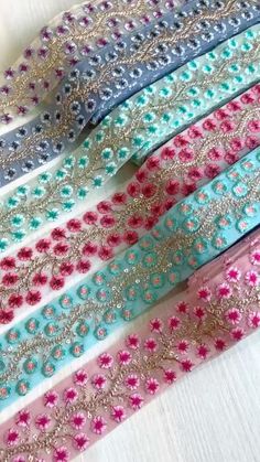 five different colored ribbons with sequins and beads on them, all lined up next to each other