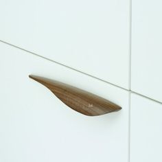 a close up of a wooden object on a white tile wall next to a drawer