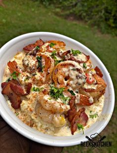 a white plate topped with shrimp and grits covered in sauce on top of green grass