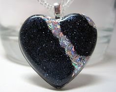 a black heart shaped pendant on a silver chain with blue and white flecks