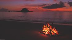 a campfire on the beach at sunset