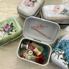 four tins filled with different types of thread and sewing supplies on a table top