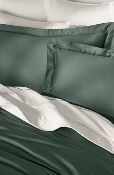 a bed with green sheets and white pillows