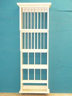 a tall white shelf sitting on top of a wooden floor next to a blue wall