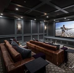 a home theater with two couches and a large screen on the wall above it