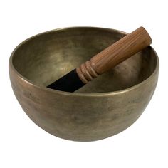 an old metal singing bowl with a wooden mallet sticking out of it's side