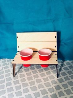 two red bowls sit on a wooden bench against a blue wall and patterned flooring