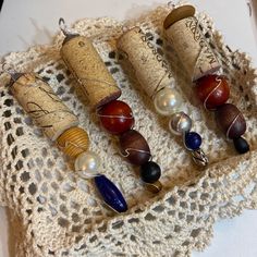 four wine corks with beads and pearls on them are sitting on a doily