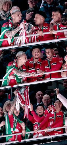 a group of people standing next to each other in front of a row of fans