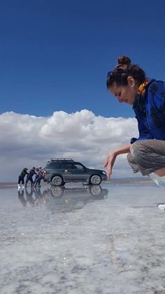 a woman on a skateboard in the middle of an icy lake with other people behind her