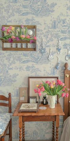 a wooden table topped with flowers next to a wall