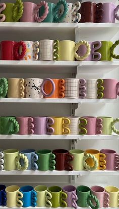 many different colored coffee mugs are on shelves