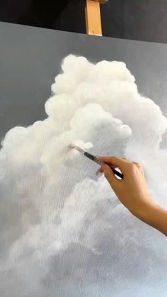 someone is using a brush to paint the clouds