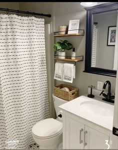 a white toilet sitting under a bathroom mirror next to a sink and a shower curtain