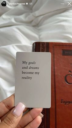 a person holding up a book with the words, my goals and dreams become my reality