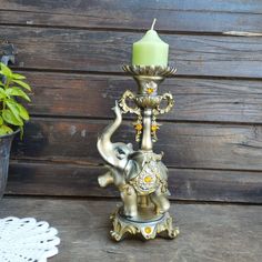 an elephant statue with a candle holder on it's side next to a potted plant