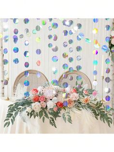 a table topped with flowers and candles next to a wall covered in sequins