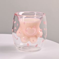 a pink candle in a glass with hearts on it