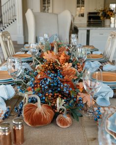 a table set with pumpkins, blue and white dishes and place settings for thanksgiving dinner