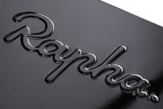 closeup of the logo on a black porsche car with chrome letters that spell out goodbye