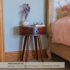 a wooden table with a vase on it next to a bed