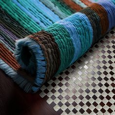 a multicolored rug is laying on top of a wooden table with woven material