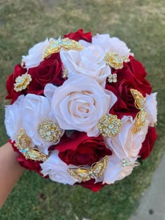 a bridal bouquet with red and white roses, brooches, and jewels