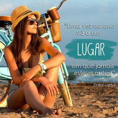 a beautiful woman sitting on top of a sandy beach next to a blue bike and wearing a hat