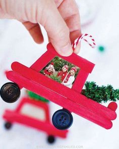 a hand is holding a small red car ornament with two pictures on it