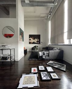 a living room filled with lots of furniture and pictures on top of a hard wood floor