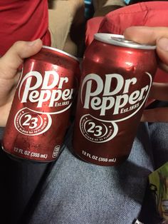 two cans of dr pepper beer sitting on the lap of someone's lap,