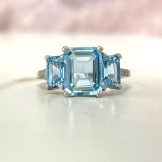 This stunning three-stone aquamarine gemstone with a approx 1.86 carat step-cut aquamarine in the center, and two step-cut aquamarines totaling approx 1.05 carats together. The three gems match perfectly in color. Diamonds on the shoulder of this ring and it is hand-crafted platinum.  ✦ AQUAMARINE SPECIFICATIONS:    Center Stone: Aquamarine  Center Aquamarine Weight: Approx 1.86 Carats  ✦ ENGAGEMENT RING SPECIFICATIONS:    Ring Material: Platinum  Stones: Aquamarine    ✦ WHAT COMES IN YOUR SHIPM Aquamarine Trilogy Ring, Blue Wedding Rings, Estate Diamond Jewelry, Gemstone Rings Vintage, Diamond Signet Ring, Aquamarine Engagement Ring, Aquamarine Jewelry, Aquamarine Rings, Platinum Ring