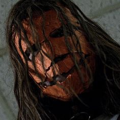 a man with long hair wearing a scary mask