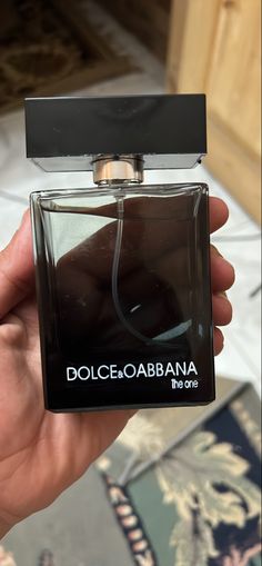 a person holding up a bottle of dolcebababaana the one perfume