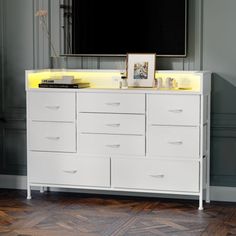 a television mounted on top of a white dresser