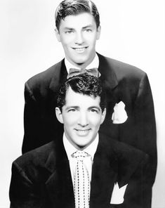 two men in suits and ties posing for a black and white photo with one wearing a bow tie