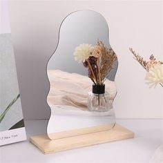 there is a vase with flowers in it and a mirror on the table next to it