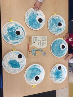 several paper plates with blue designs on them and children's hands reaching for one