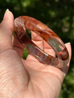 The inner diameter of the bracelet:58.5mm Wrap your wrist in the enchanting radiance of our Crimson Glow: Hematoid Quartz Bangle Bracelet. Crafted from mesmerizing hematoid quartz, this bracelet exudes a warm and inviting aura. Its deep crimson hues and unique patterns create a captivating visual display, making it a versatile accessory for any occasion. Handcrafted with meticulous care, the Crimson Glow Bangle is more than just jewelry; it's a symbol of vitality and inner strength. Whether worn Adjustable Clear Bangle Jewelry, Adjustable Clear Bangle Bracelet, Adjustable Clear Bangle Bracelets, Clear Bangle Bracelet As A Gift, Clear Bangle Bracelet For Gifts, Handmade Clear Bracelets, Glow Bracelets, Hematoid Quartz, Visual Display