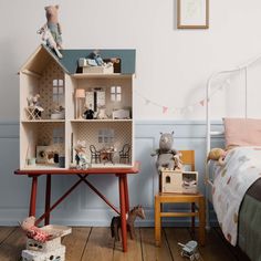 a doll house sitting on top of a wooden table next to a bed in a room