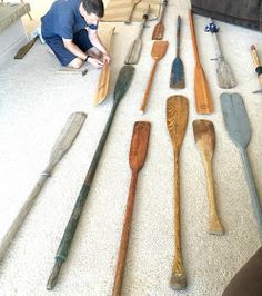 a man sitting on the floor next to lots of wooden spoons