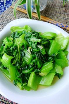 a white bowl filled with green vegetables on top of a table