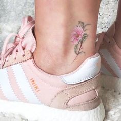 a close up of a person's foot with a flower tattoo on the ankle