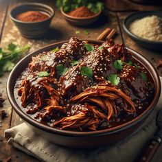 a bowl filled with meat covered in sauce and garnished with cilantro