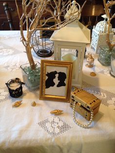 a table topped with pictures and other items on top of a cloth covered tablecloth