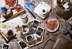 a table topped with lots of pictures and other things on top of it, next to a camera