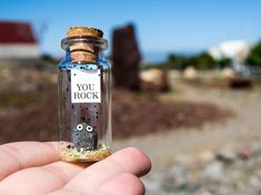 a person holding a tiny bottle with a message in it that says you rock on the inside